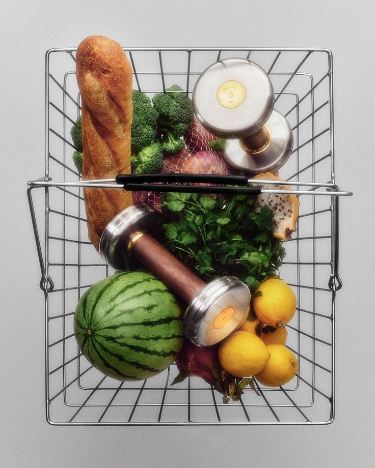 Cesta de alimentos saudáveis com halteres e nutrição esportiva